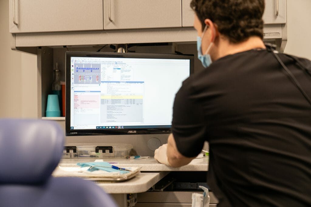 Dr. Hickey in surgical mask looking at computer monitor